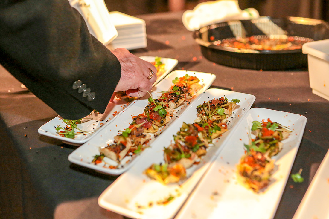 person reaching for food samples at Taste of the Bay event