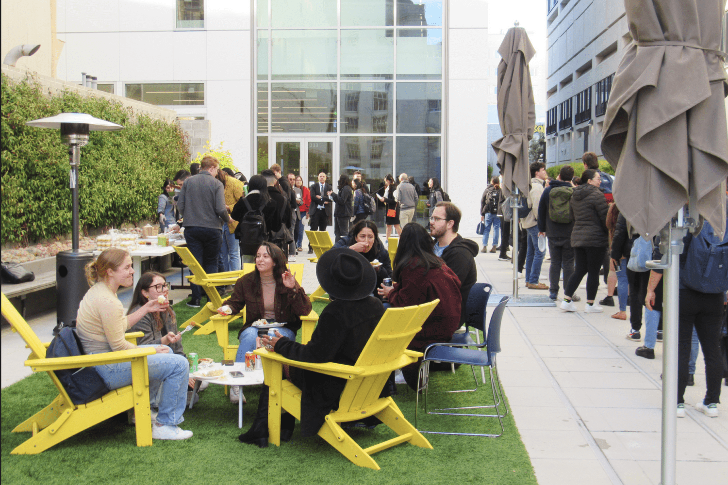Students talking while sitting and standing around outside in courtyard surrounded by buildings